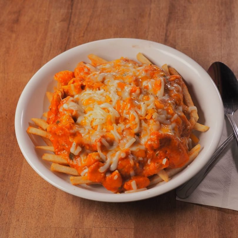 Pataka Indian Fusion Cuisine's cheesy fries, topped with a vibrant orange sauce and melted cheese.